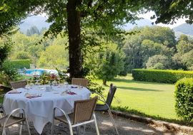 Terrasse ensoleillée table ronde, recouverte d'une nappe, chaises en osier, aux textures douces et légèrement courbées.