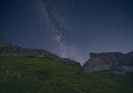 Le paysage offre une vue sur le ciel étoilé, avec des variations tandis qu'en dessous, on aperçois des montagnes.