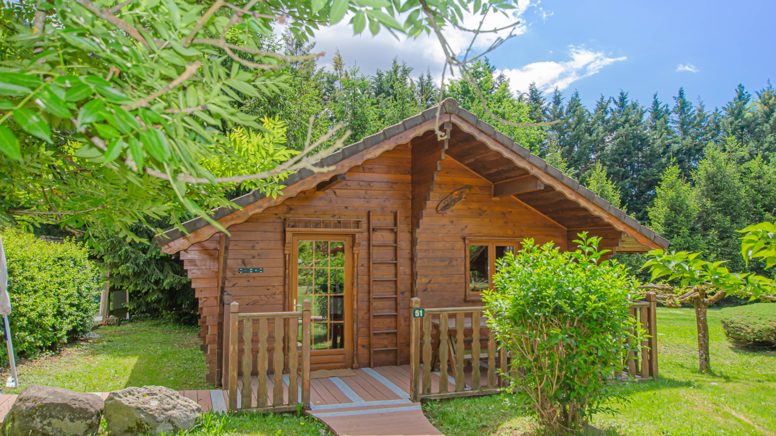 Ce chalet en bois, au toit pentu, est niché dans un écrin de verdure.