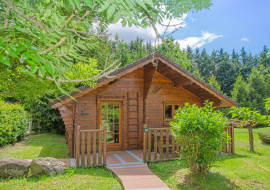 Ce chalet en bois, au toit pentu, est niché dans un écrin de verdure.