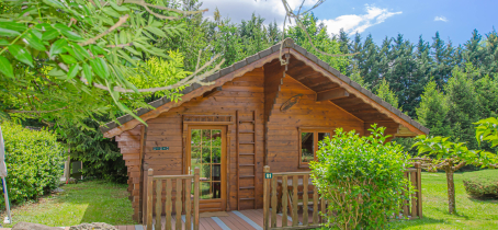 Ce chalet en bois, au toit pentu, est niché dans un écrin de verdure.