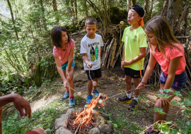 groupes d'enfants en train de faire griller des chamallows en forêt