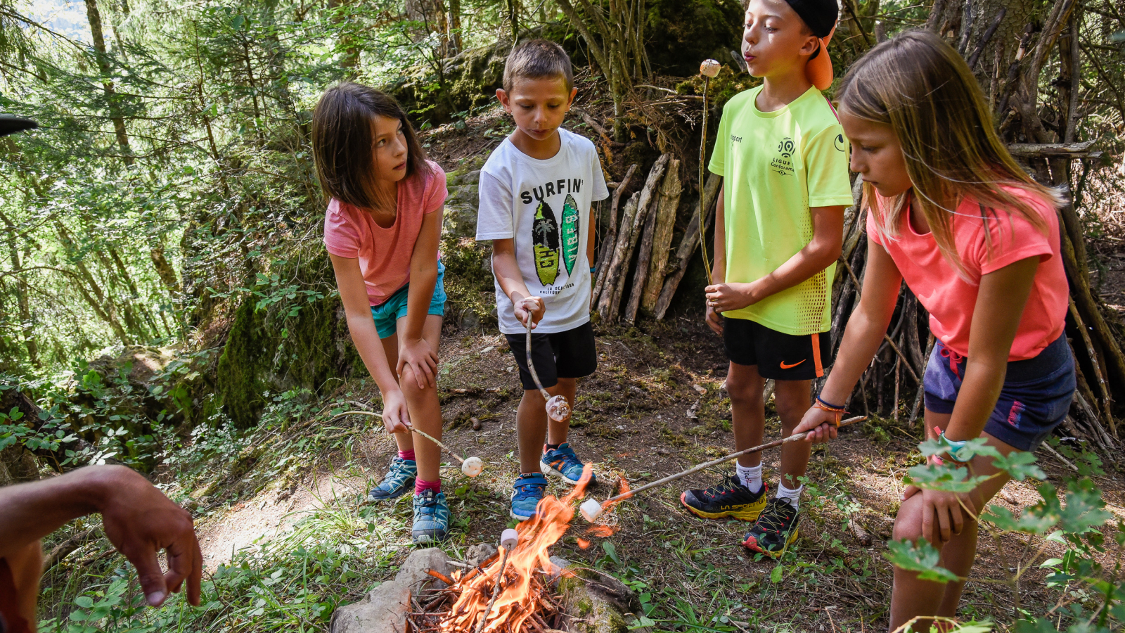 plusieurs enfants qui font griller du chamallow en forêt