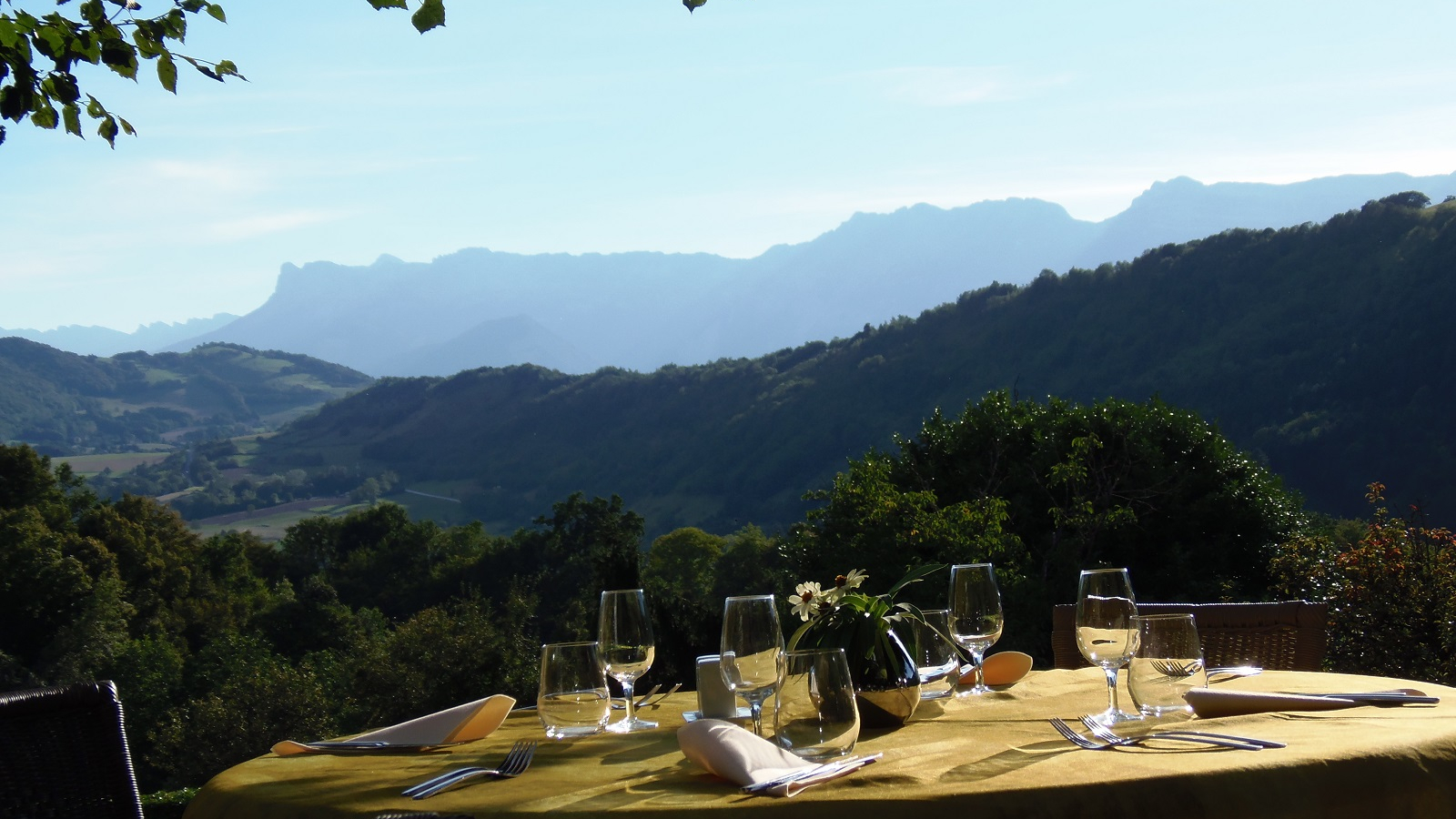 Table joliment dressée en terrasse avec une vue dégagée et panoramique sur le massif du Vercors.