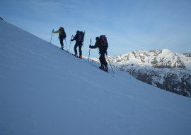 vue de dos de 3 skieurs de randonnée en montée