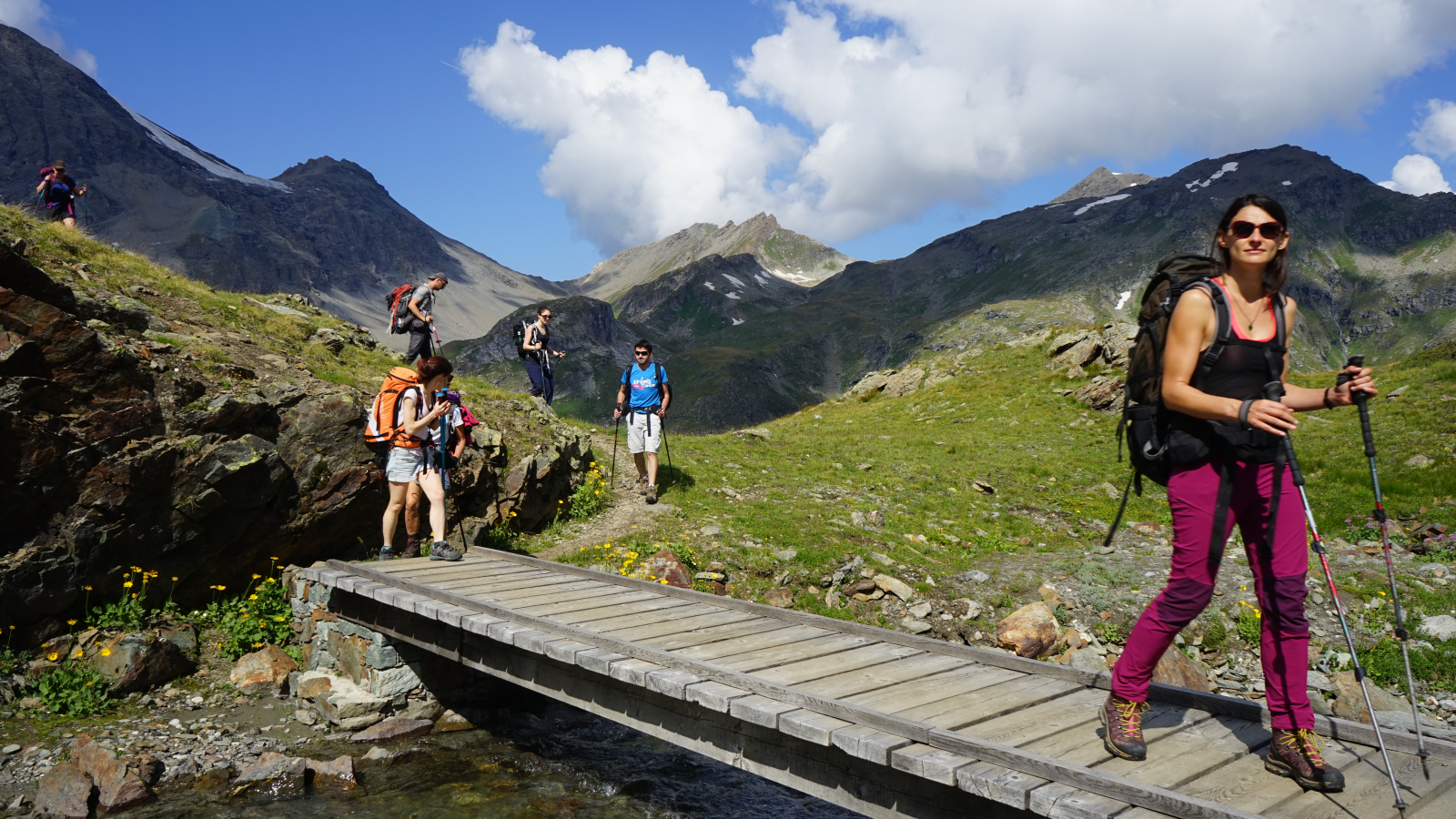 Randonneurs sur passerelle en bois en montagne l'été