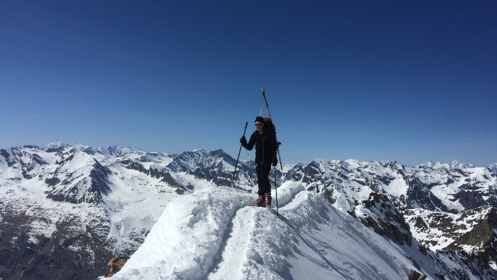 Skieur de randonnée au sommet d'une crete avec une vue panoramique sur les montagnes