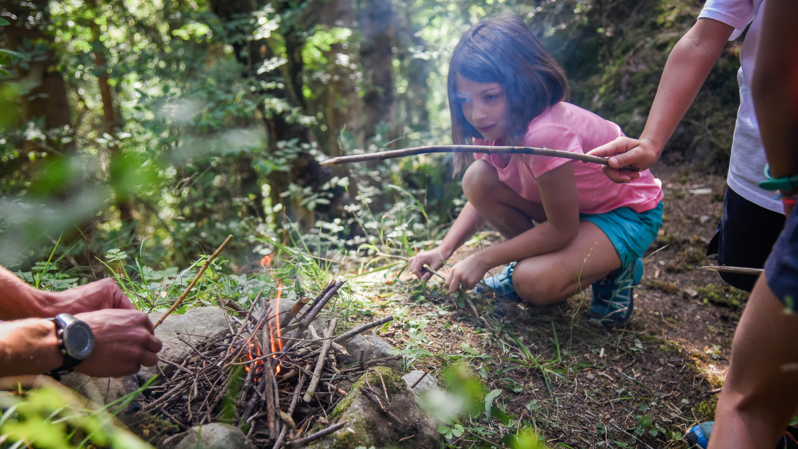 petite fille qui allume un feu de bois en forêt