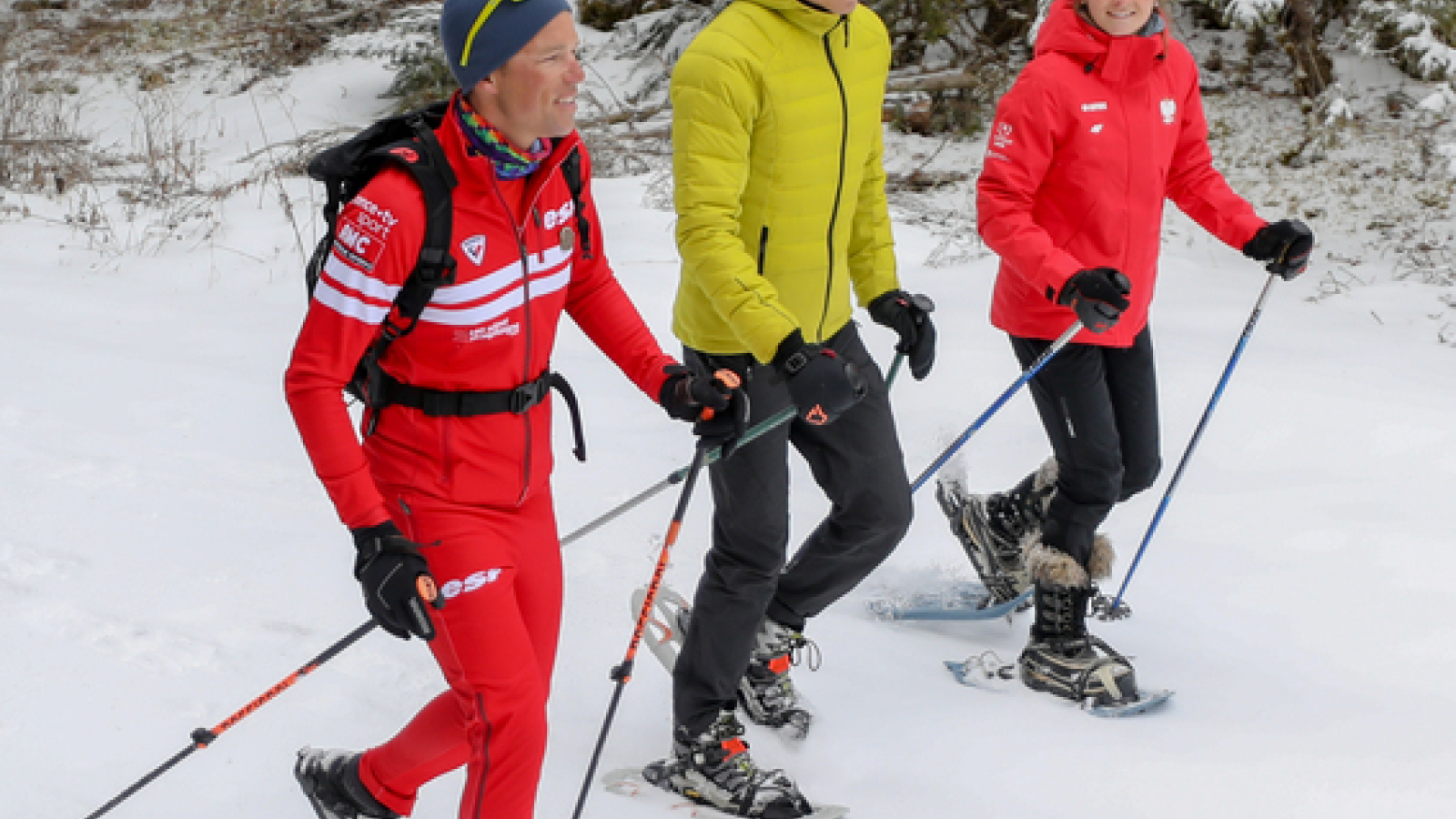 Groupe de raquettistes évoluant dans un décor hivernal en pleine forêt, encadré par un moniteur de l'ESF