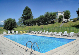 Piscine extérieure rectangulaire, entourée de chaises longues et d'une terrasse ensoleillée.