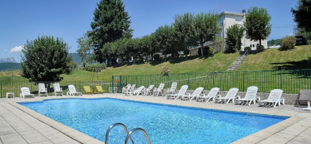 Piscine extérieure rectangulaire, entourée de chaises longues et d'une terrasse ensoleillée.