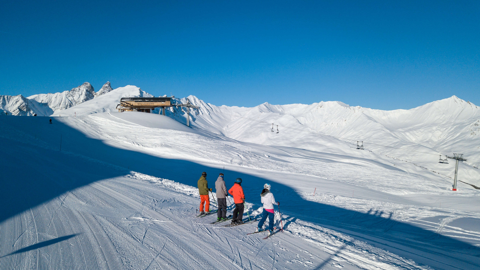 4 adultes en train de skier à Valloire sur le domaine Galibier thabor sétaz des pré, vue sur leTélésiège de Cornafond et sur les Aiguilles d’Arves