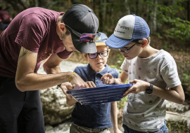 2 enfants et un adulte regardent dans le tamis à la recherche de pépites d'or