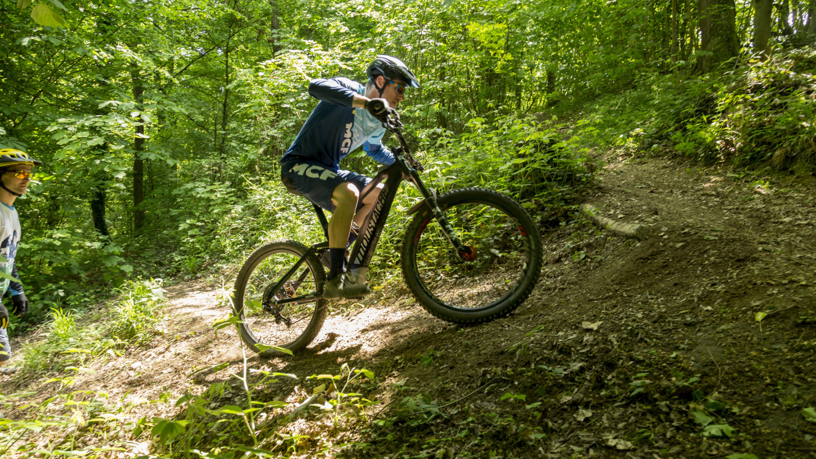 un cycliste en train de monter un sentier single en forêt