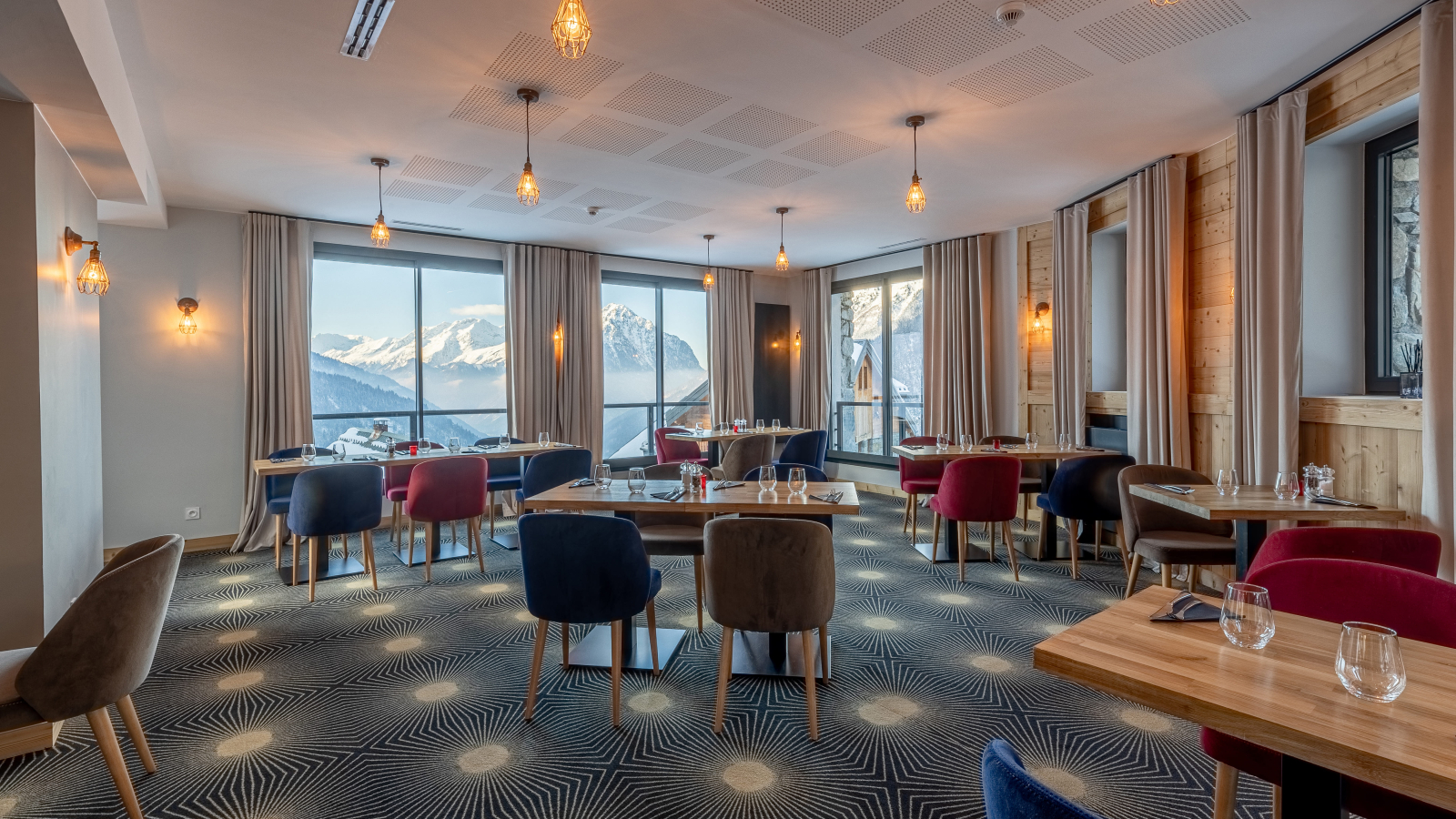 Salle de restaurant avec grandes fenêtres vue sur les montagnes l'hiver.