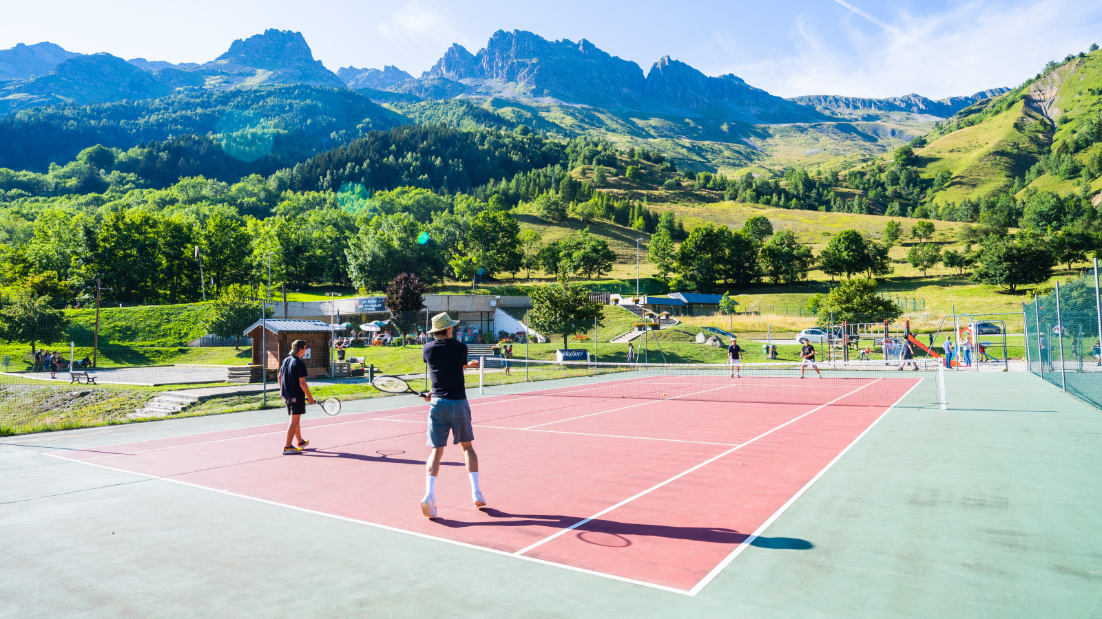 Terrain de tennis au soleil face aux montagnes.