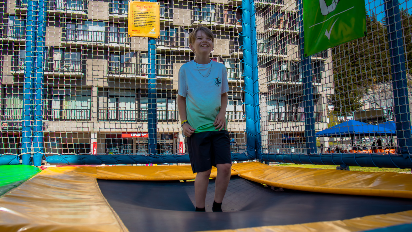 A boy on the trampoline with one of the Flaine resort buildings in the background